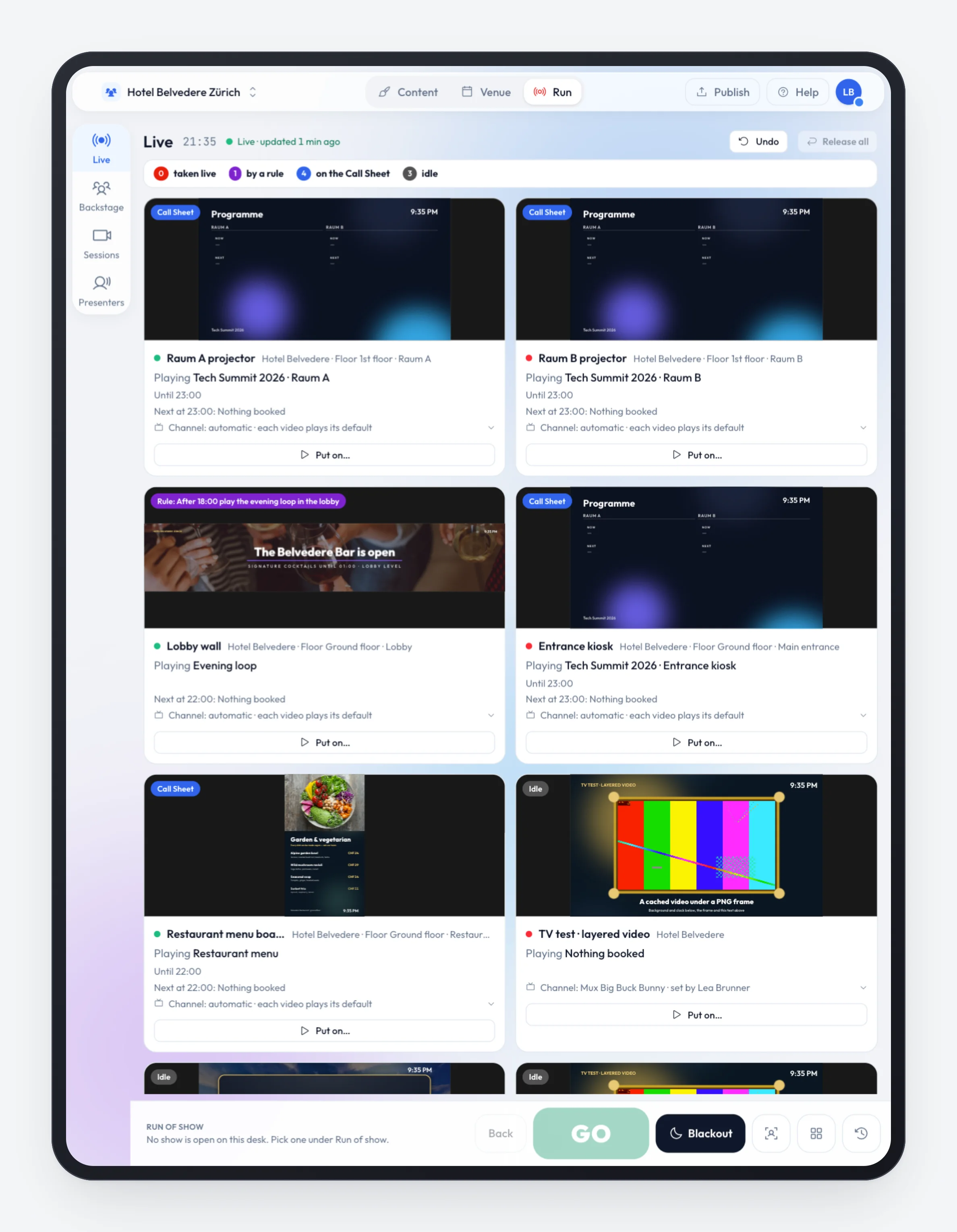 The Live board on a tablet in portrait: stage tiles in two columns with live pictures — Raum A and Raum B projectors, Lobby wall under an evening rule, Entrance kiosk, Restaurant menu board and TV test — and a bar at the bottom with GO, Blackout and quick panels.